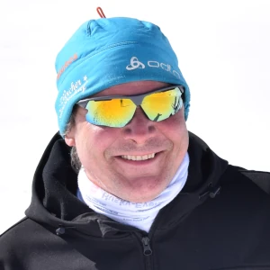 Nahaufnahme von Phil, dem Musher von Wild Swiss Adventure, mit Sonnenbrille, Mütze und breitem Lächeln – freundlich und authentisch.
