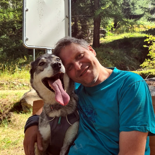 Team-Moment im Wald - Phil und Husky Storm auf der Bank, Kopf an Kopf, Symbol für Vertrauen im Rudel