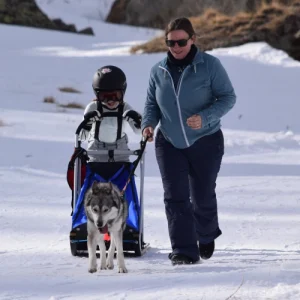 Mutter und Kind bei den Kids Days auf der Triftalp in Saas Grund – das Kind lenkt den Schlitten mit einem Husky, während die Mutter vorne den Hund sichert.